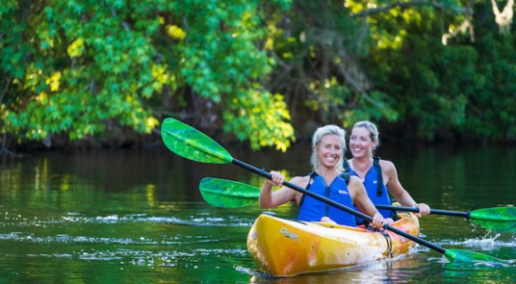 two women kayaking on the lagoon with greenery in the background