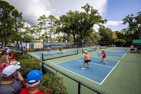 pickleball players in a tournament on the court with spectators looking out