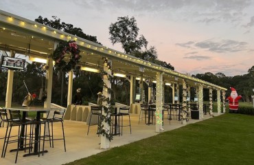 view of the driving range with lights along the roof and poles with the sunset in the background