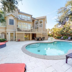 backyard of rental home with deck, lounge chairs, and pool