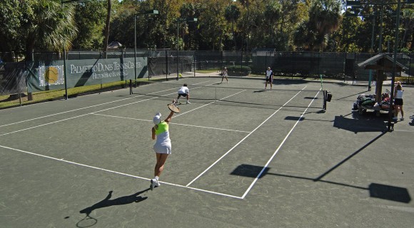 Four people playing tennis on clay court