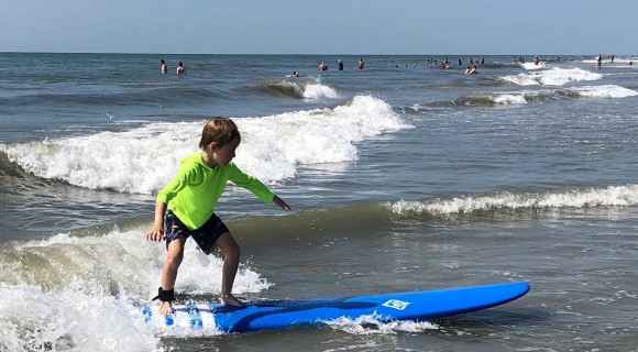 Young boy surfing in shallow ocean water