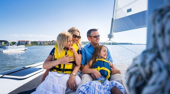 family snuggled and smiling enjoying a cruise on a sailboat