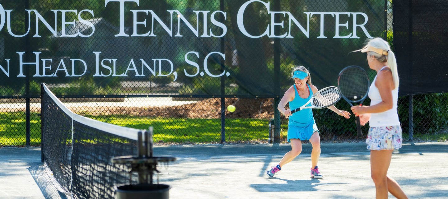 two women actively playing tennis at PD tennis center